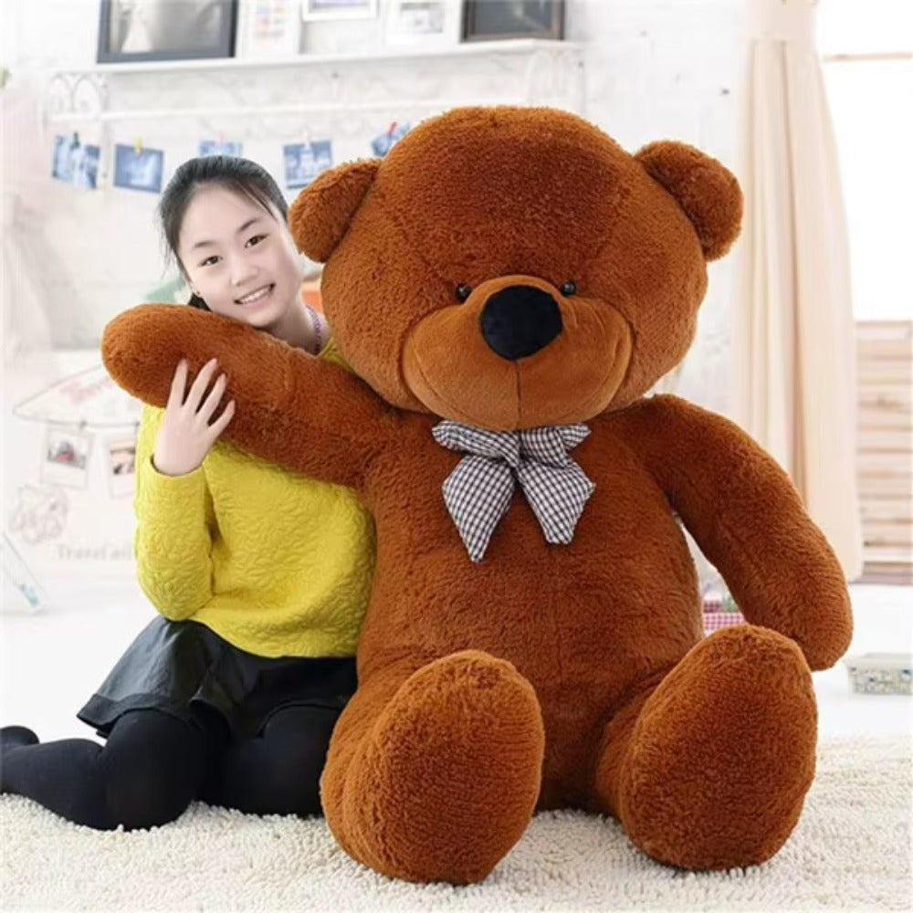 Giant dark brown teddy bear with a plaid bow hugging a girl