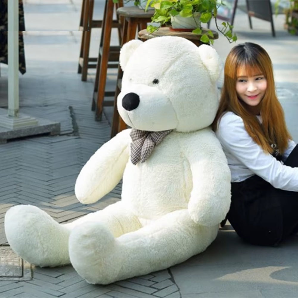Giant white teddy bear with a plaid bow sitting outdoors next to a woman